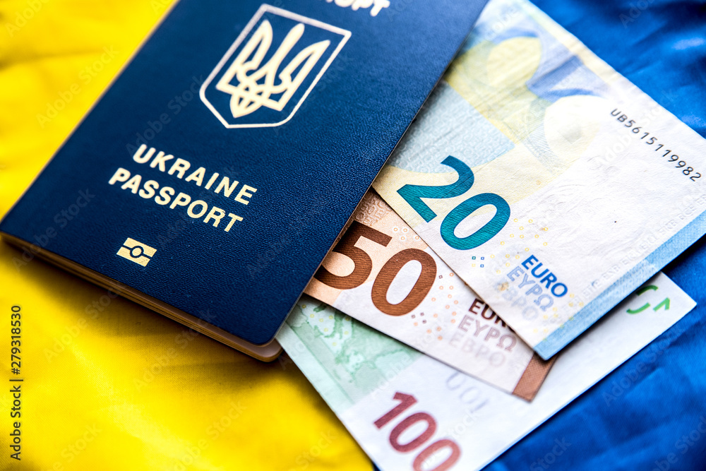 Obraz premium Ukrainian passport on the background of the Ukrainian flag with euro banknotes of different denominations.
