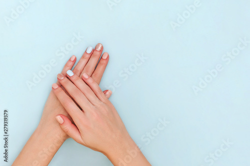 Woman's hands with pastel manicure on blue background. Copy space.