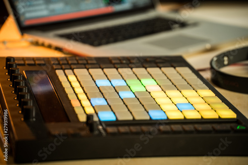 Electronic music production in a home studio. Closeup of coloured LED pads on a midi controller.