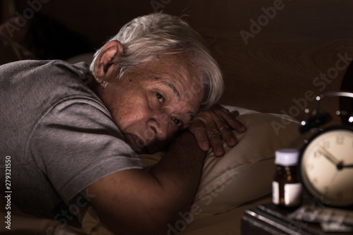 Depressed senior man lying in bed cannot sleep from insomnia