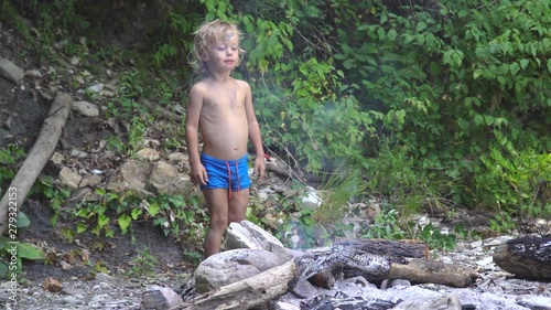 little boy by the fire in the forest. summer, adventure, childhood. concept - vacation. photo