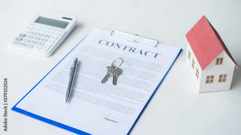 House model, calculator and house key lying on real estate contract, home loan and investment concept House model, calculator and house key lying on real estate contract, home loan and investment concept