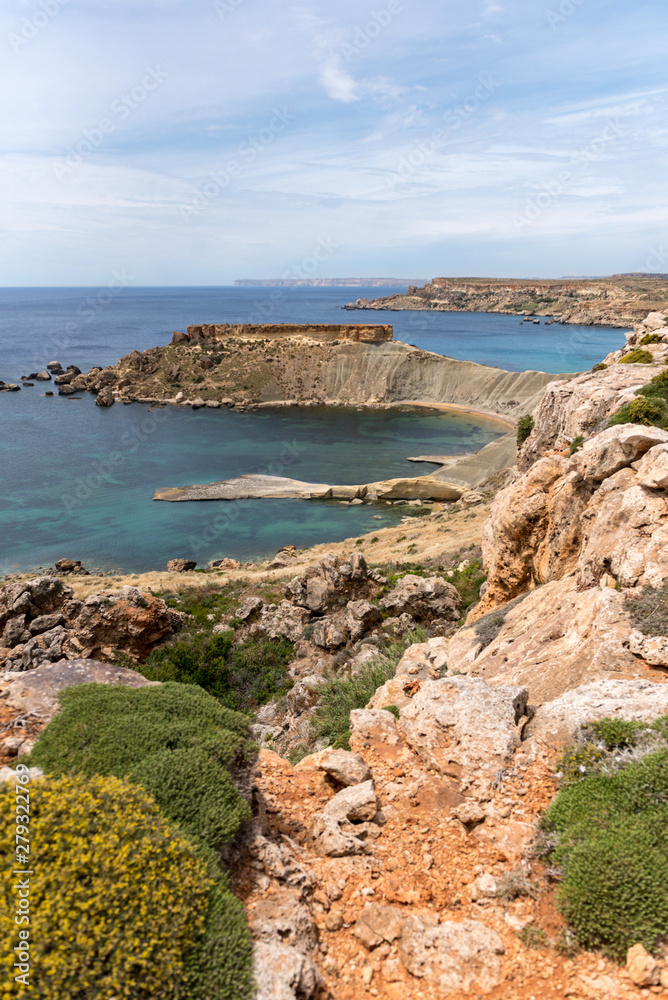 Mgarr, Malta - Panorama of Gnejna bay, the most beautiful beach in Malta at sunset with beautiful colorful sky and golden rocks taken from Ta Lippija