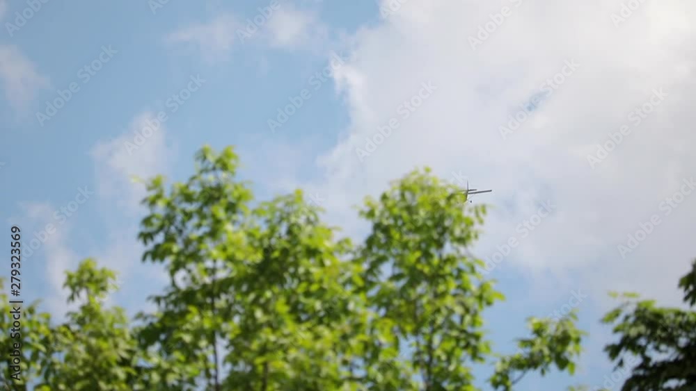 Small Airplane Flies Away Against Blue Sky With White Clouds LOW ANGLE Small Airplane Flies Away Against Blue Sky With White Clouds LOW ANGLE