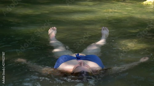 Attractive middle-aged woman in a bathing suit relaxing in the water. swimming in a mountain river. human and nature. photo