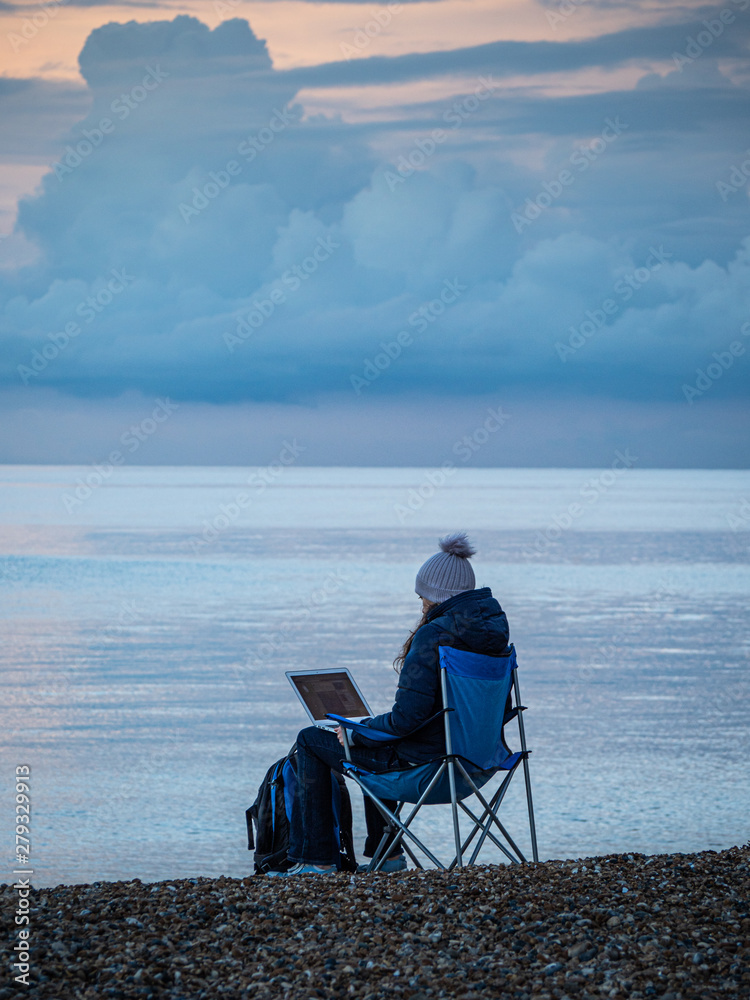 Young attractive Woman Working On Her Laptop At The Seaside