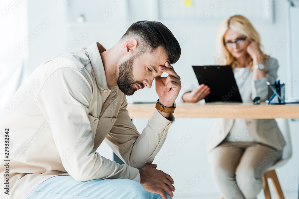 Obraz premium selective focus of frustrated man sitting near blonde recruiter