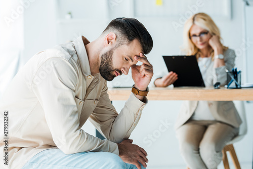 selective focus of frustrated man sitting near blonde recruiter