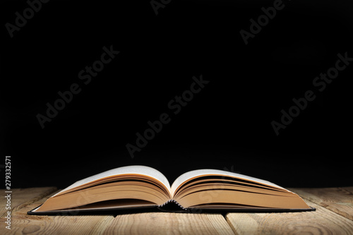 open book on a wooden table and black background  with copy space for your text
