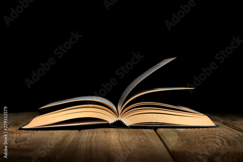 open book on a wooden table and black background  with copy space for your text