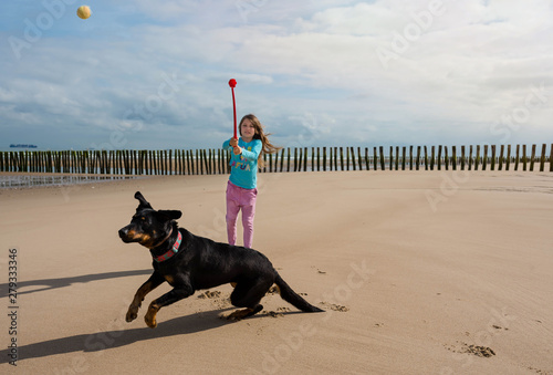 young girl playing throwing a ball at her dog photo