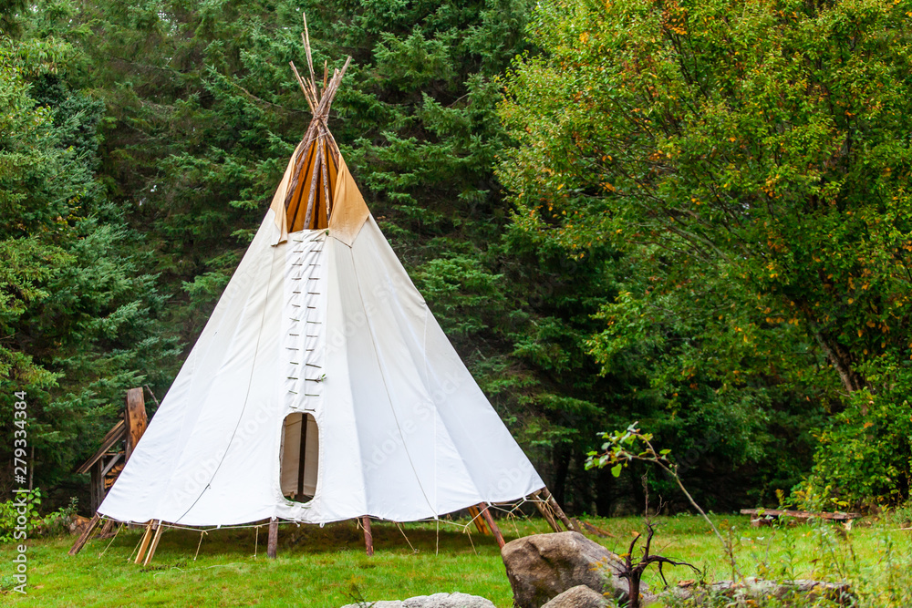 Fusion of cultural & modern music event. A rustic tipi tent is viewed by  woodland, similar to that of Native American tribes, during a festival  fusing ancient culture with modern music. Photos