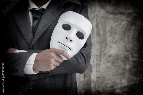 Businessman holding white mask in his hand dishonest cheating agreement.Faking and betray business partnership concept photo