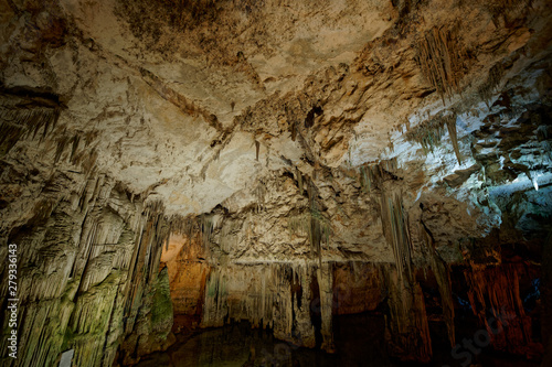 Imposing stalactites and stalacmites reflecting in a small underground lake inside the limestone cave (Tropfsteinhöhle) Grotta di Nettuno in Sardegna (Italy) 