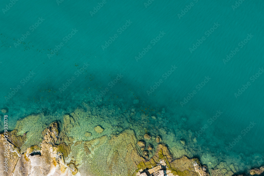 Fototapeta premium Aerial view of rocky seaside. Rocky stones in the ocean. Aerial photography of beautiful rocky seashore.