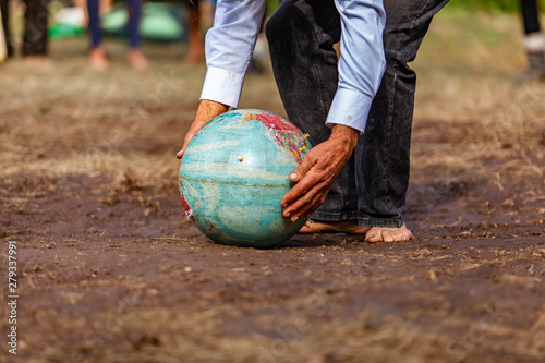 Fusion of cultural & modern music event. Hands of an elderly man are viewed closeup, as he picks an earth globe off the soil ground outdoors, barefooted hippy at cultural celebration. photo