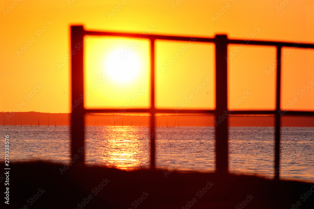Blurred silhouette of a fence on a seashore during the sunset