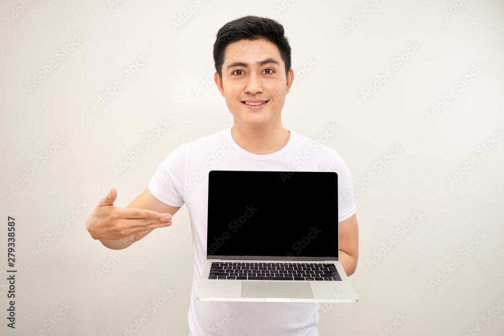 Smiling young asian man dressed in shirt showing blank screen laptop computer over white background Smiling young asian man dressed in shirt showing blank screen laptop computer over white background
