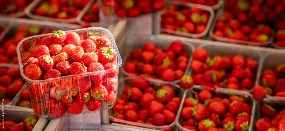 Strawberries in plastic containers at farmers market, background, texture.