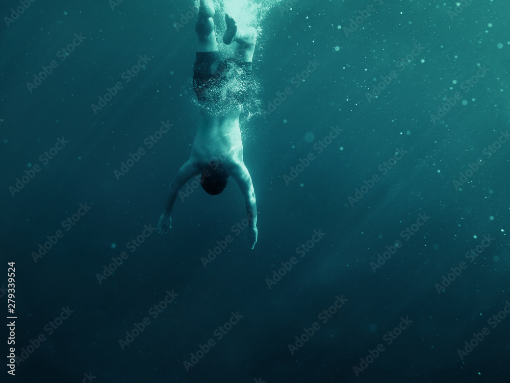 Man falling into the water. Underwater shot. Vacation, sports and active lifestyle risk concept.