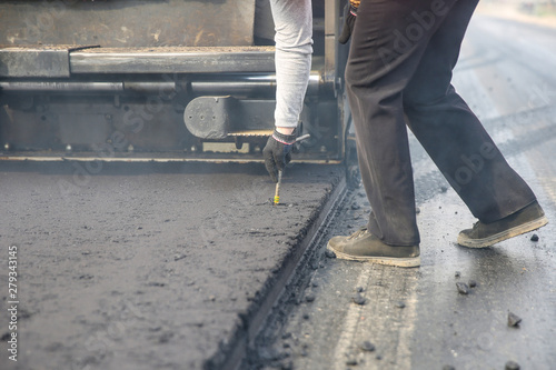 asphalt paving works. road worker checks the depth of paving the roadway