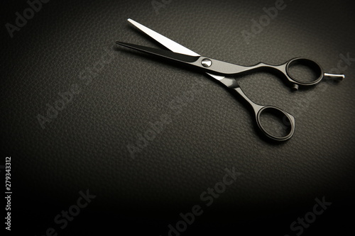 black hairdressing scissors on black background with copy space.