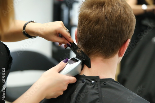 the barber makes the cut by hair clipper. the stylist makes the haircut for male close up.