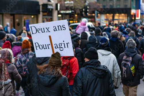 Environmental activists march in city. A French sign is viewed closeup, saying two years to act, held by an environmentalist above a large crowd of demonstrators on an urban street, with copy space. © Valmedia