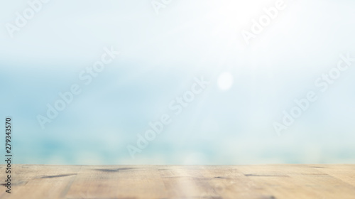 Terrace at Ocean. Wooden empty table lit by soft sunlight in blur. Blurred blue sea background. Photo with copy space.