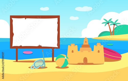 A sand castle stands on the beach by the summer sea next to childrens toys.