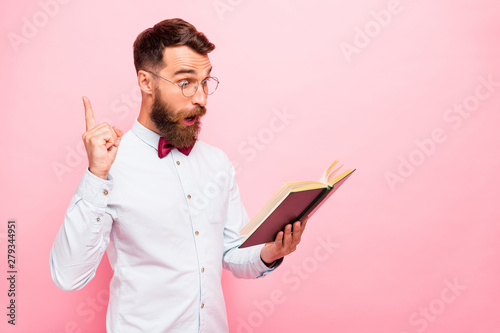 Photo of thoughtful intellectual person holding opened paper literature in hands pointing fore-finger up isolated pastel background