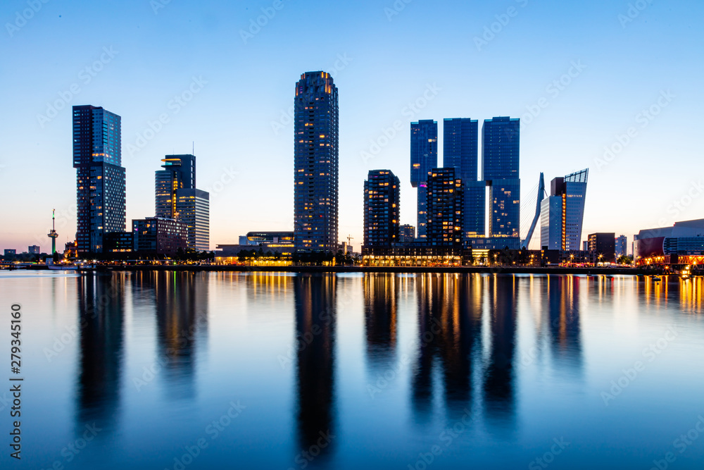 Rotterdam city Netherlands illuminated skyscrapers, reflections on the water, sunset time, blue clear sky