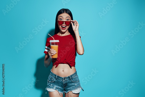Surprise! Attractive young Asian woman smiling while standing against blue background
