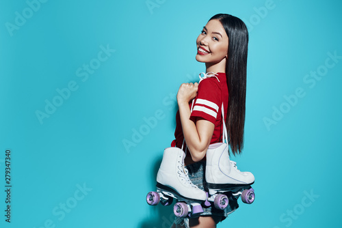 Ready to have fun. Attractive young Asian woman smiling and looking at camera while standing against blue background