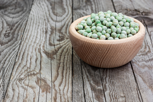 Dried green peas in wooden bowl on wooden background. Peas in a bowl. Natural decoration with green pea.