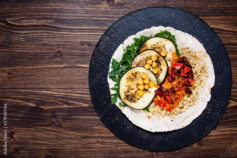 Groats with sauce and vegetables on tortilla