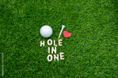 Golf hole in one with golf ball and tee on green grass.