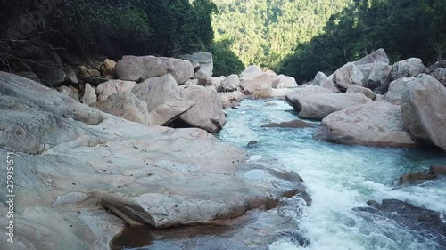 Flying on the drone above the wild waterfall in tropical palm forest. Beautiful landscape of green jungle and stream of mountain river. Cascade of water around nature. Travel concept in Asia.