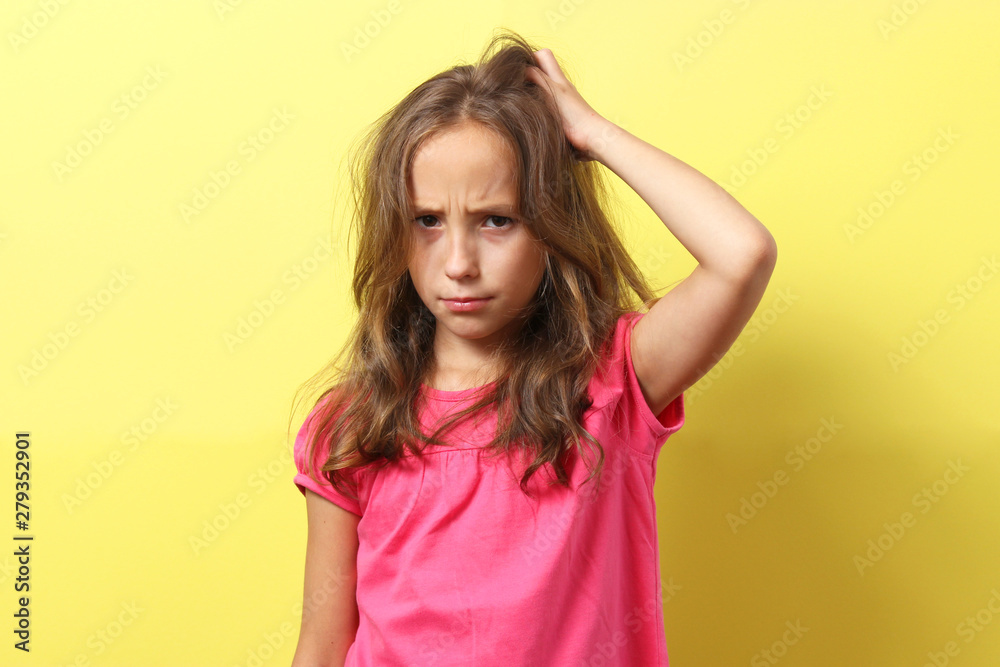 The girl is scratching her head on a colored background. 