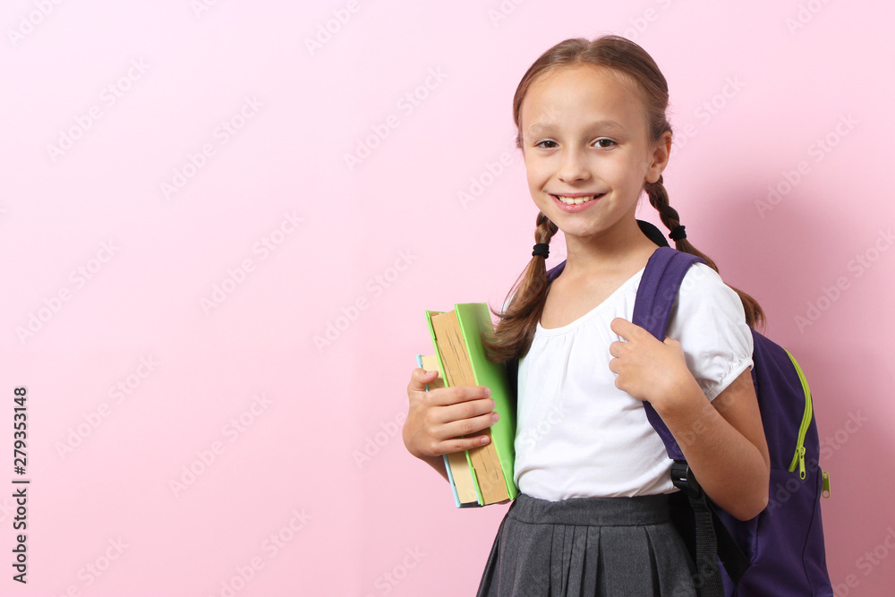 Cute smiling schoolgirl with a school backpack on a colored background. Back to school concept Cute smiling schoolgirl with a school backpack on a colored background. Back to school concept