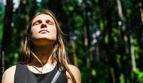  Outdoor portrait of young teenager brunette girl with long hair looking up in forest
