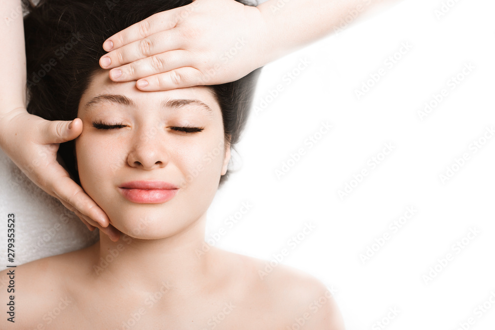 Close up upper view of a beautiful woman having anti age facial massage in a wellness spa resort while traveling in her vacation time. Close up upper view of a beautiful woman having anti age facial massage in a wellness spa resort while traveling in her vacation time.