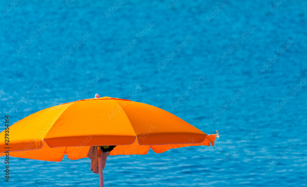 Orange beach umbrella by the sea in summer day