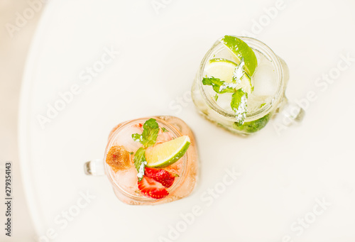 Lemonade drinks with fresh lime, mint and strawberry in glasses. photo