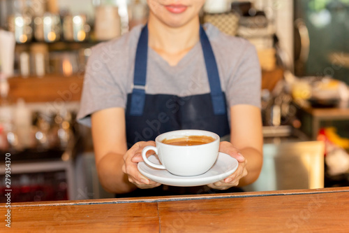 Waitress serving coffee while standing in coffee shop counter.