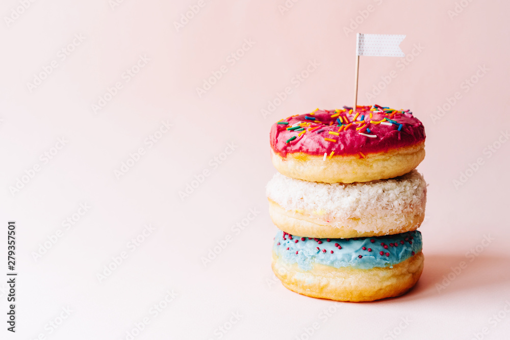 Three multi-colored glazed cream donuts stacked on each other Three multi-colored glazed cream donuts stacked on each other