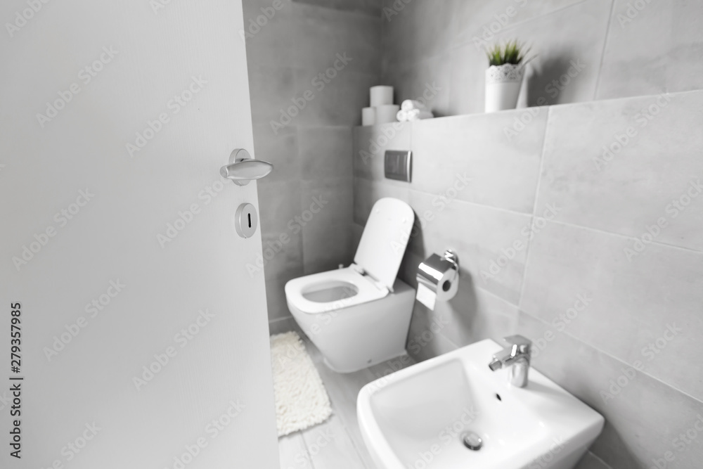 Half-open door to luxury bathroom with white ceramic bidet and toilet Half-open door to luxury bathroom with white ceramic bidet and toilet