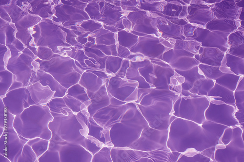 Rippled pattern of clean water in a purple swimming pool for background
