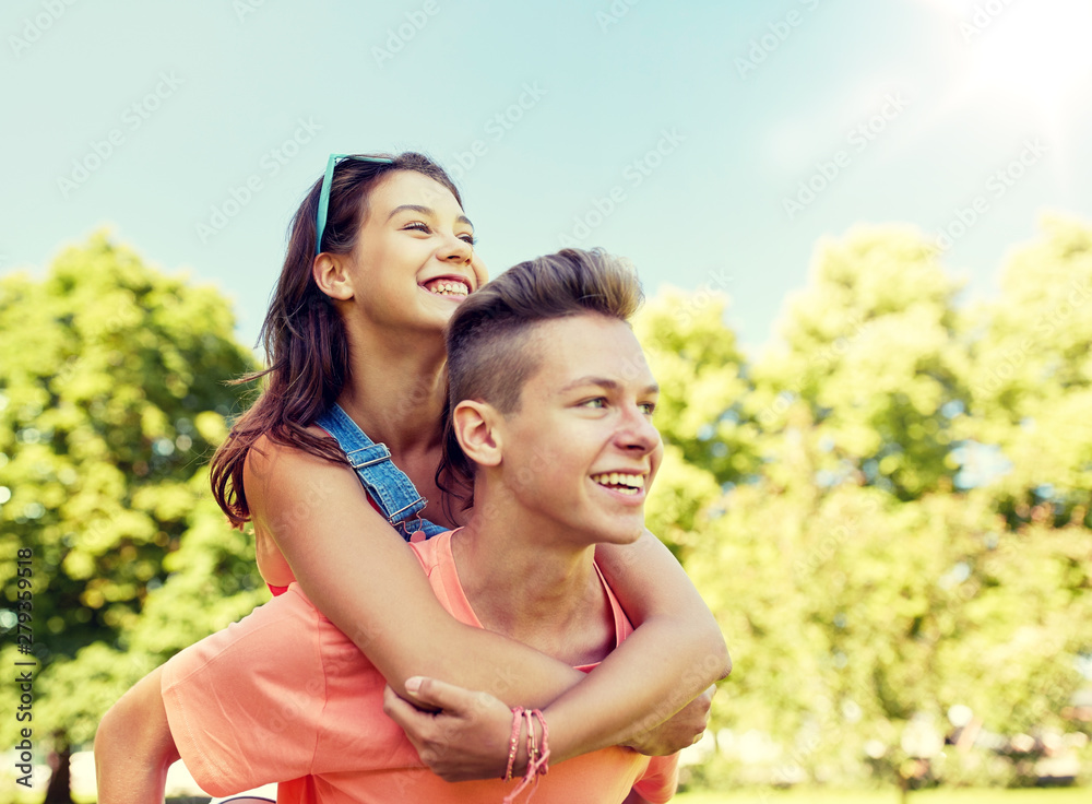 holidays, vacation, love and people concept - happy smiling teenage couple having fun at summer park holidays, vacation, love and people concept - happy smiling teenage couple having fun at summer park