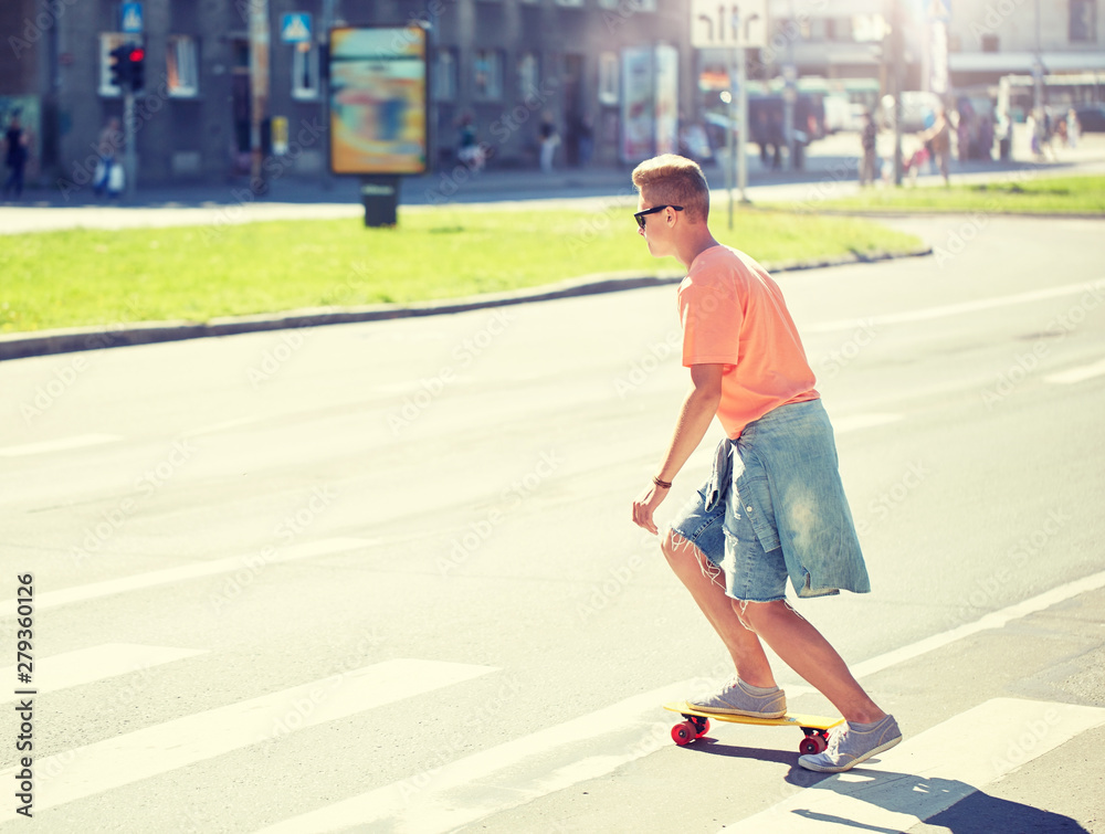 summer holidays, extreme sport and people concept - teenage boy riding short modern cruiser skateboard on crosswalk in city summer holidays, extreme sport and people concept - teenage boy riding short modern cruiser skateboard on crosswalk in city